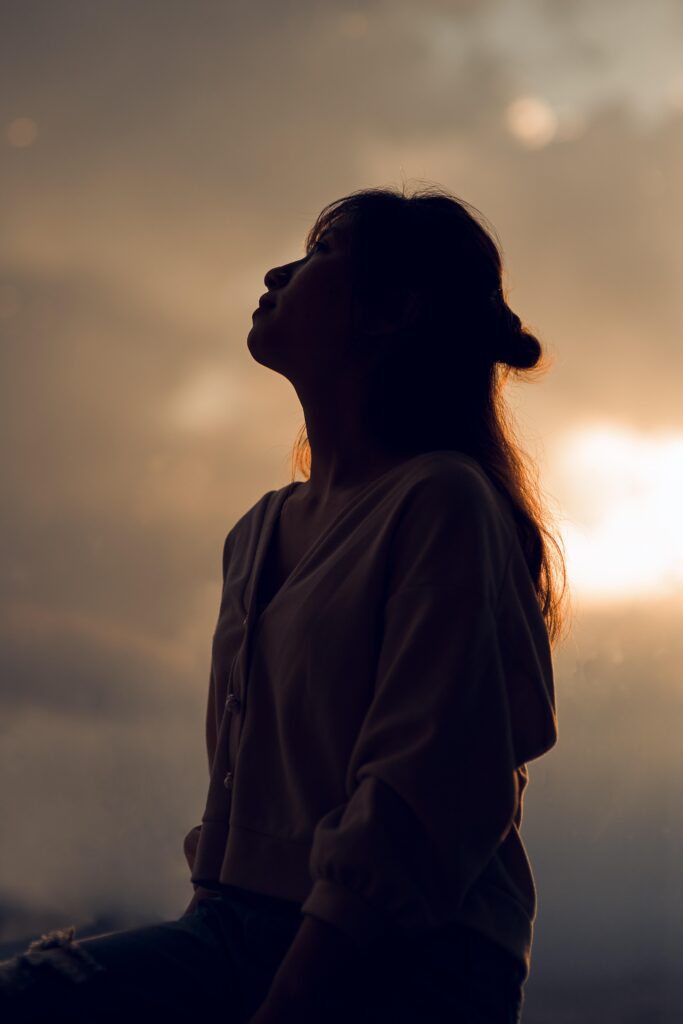 Femme sereine respirant profondément au coucher du soleil, symbolisant l'apaisement retrouvé grâce à l'hypnose